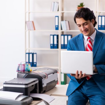 best free internet online fax service man in blue suit with laptop in hands near fax machine in office folders in the background gotfreefax